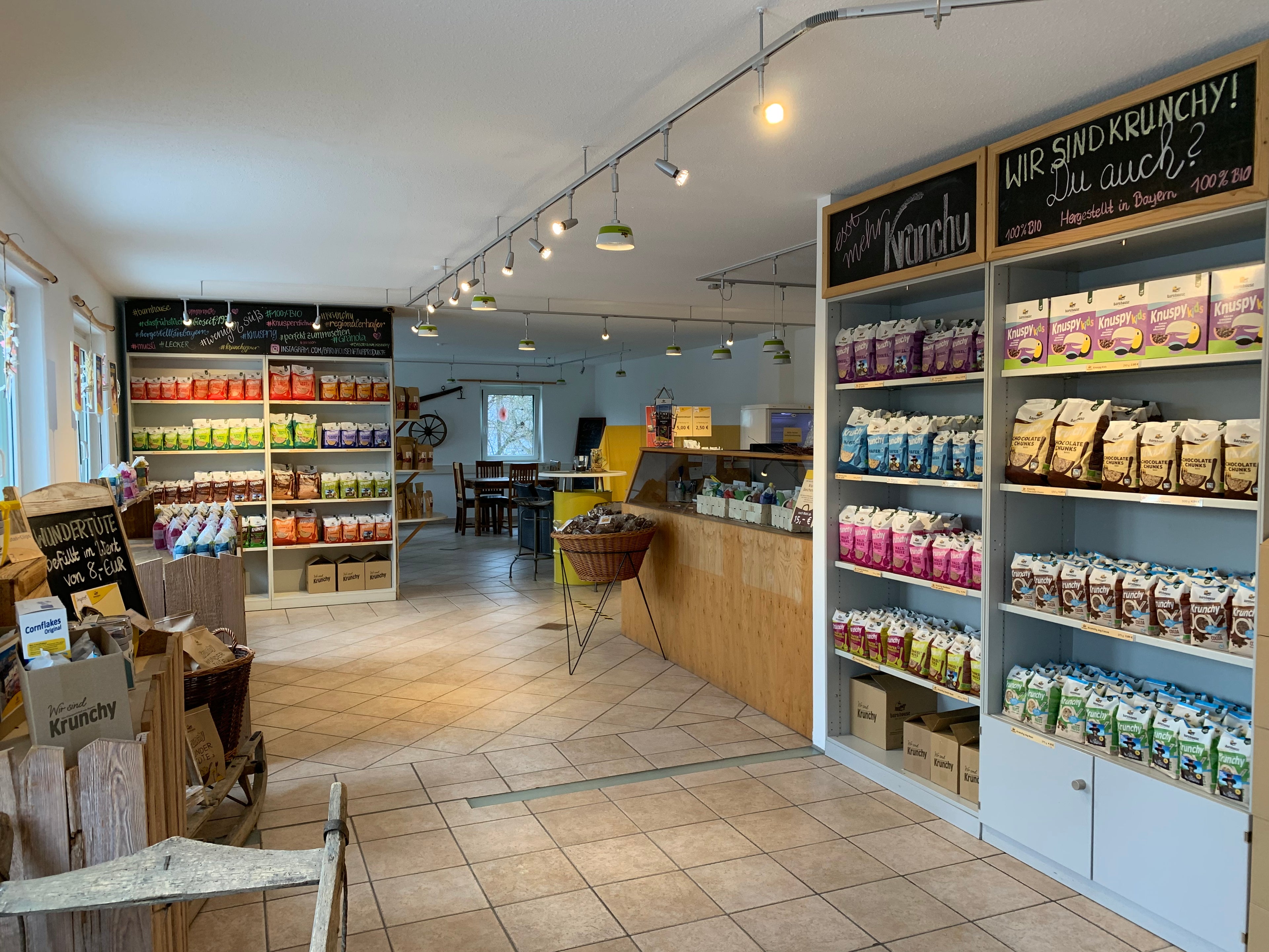 Ein Blick in den Werksverkauf mit Verkaufstheke und zwei Regalen mit Krunchy von Bio-Knuspermüsli-Hersteller Barnhouse.