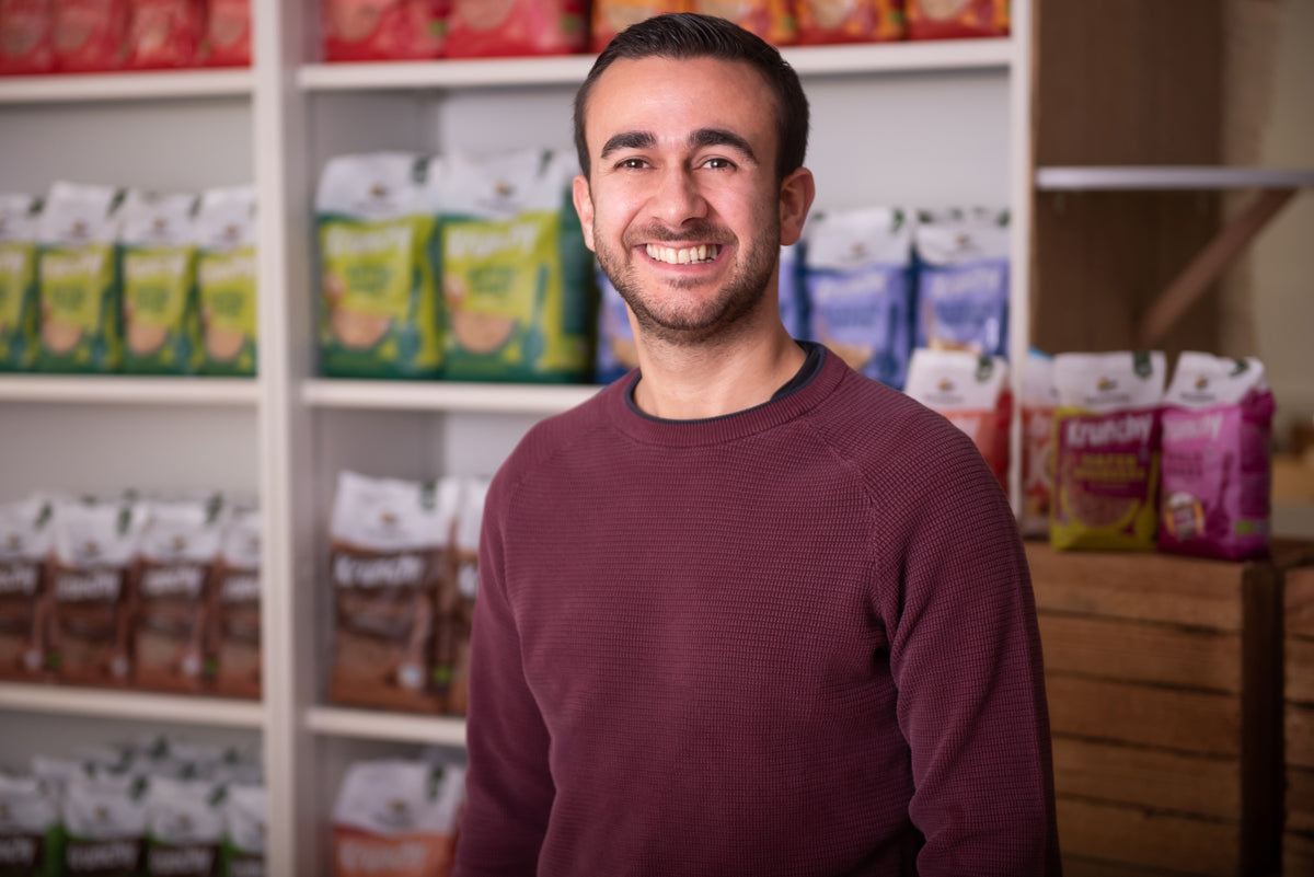 Daniel vom Onlinemarketing lächelnd vor einem Regal mit Krunchy von Bio-Knuspermüsli-Hersteller Barnhouse.