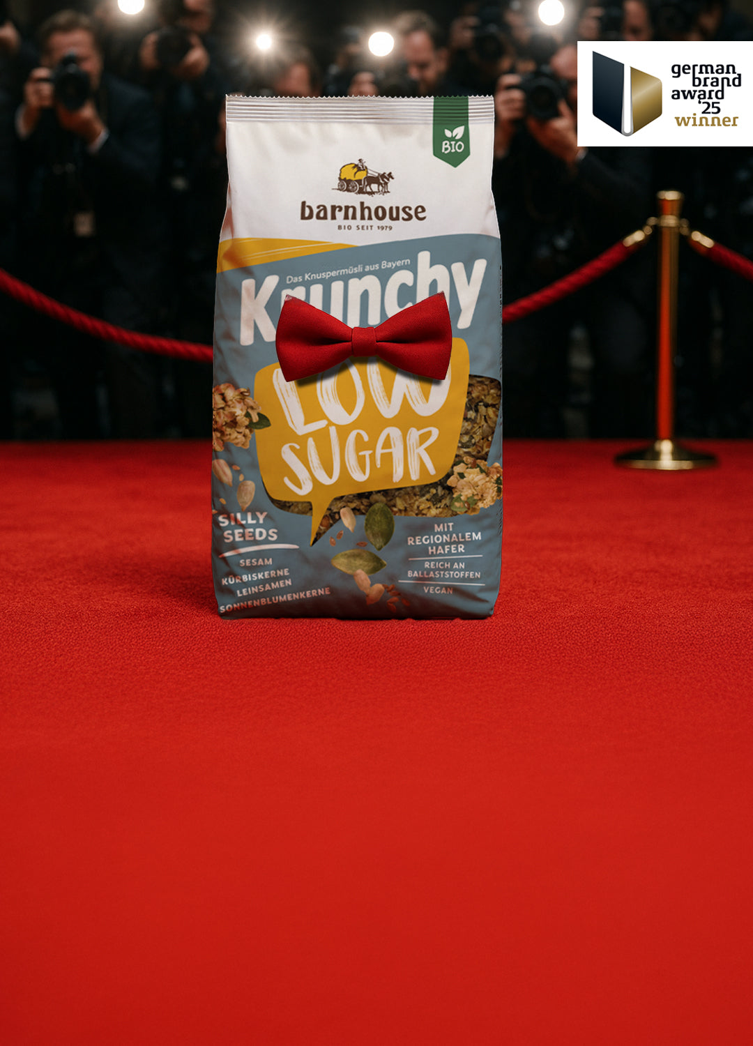 Beutel Krunchy Low Sugar Silly Seeds mit roter Fliege, der auf einem roten Teppich vor lauter Paparazzi steht. Rechts oben ist das German Brand Award 25 Winner Label abgebildet.