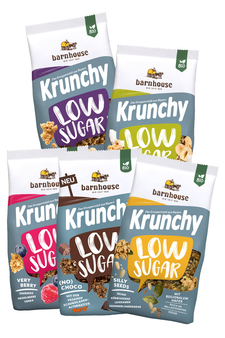 Blick von vorne auf die schräg angeordneten Packshots der fünf Low Sugar Krunchys Plain Grain, Crazy Nuts, Very Berry (No) Choco und Silly Seeds von Bio-Knuspermüsli-Hersteller Barnhouse.