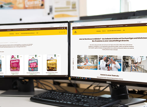 Blick auf einen Barnhouse Arbeitsplatz mit zwei Bildschirmen. Links ist der Barnhouse Onlineshop zu sehen, rechts die Jobübersicht von Barnhouse. Im Vordergrund sind noch eine Tastatur und eine Maus zu sehen.