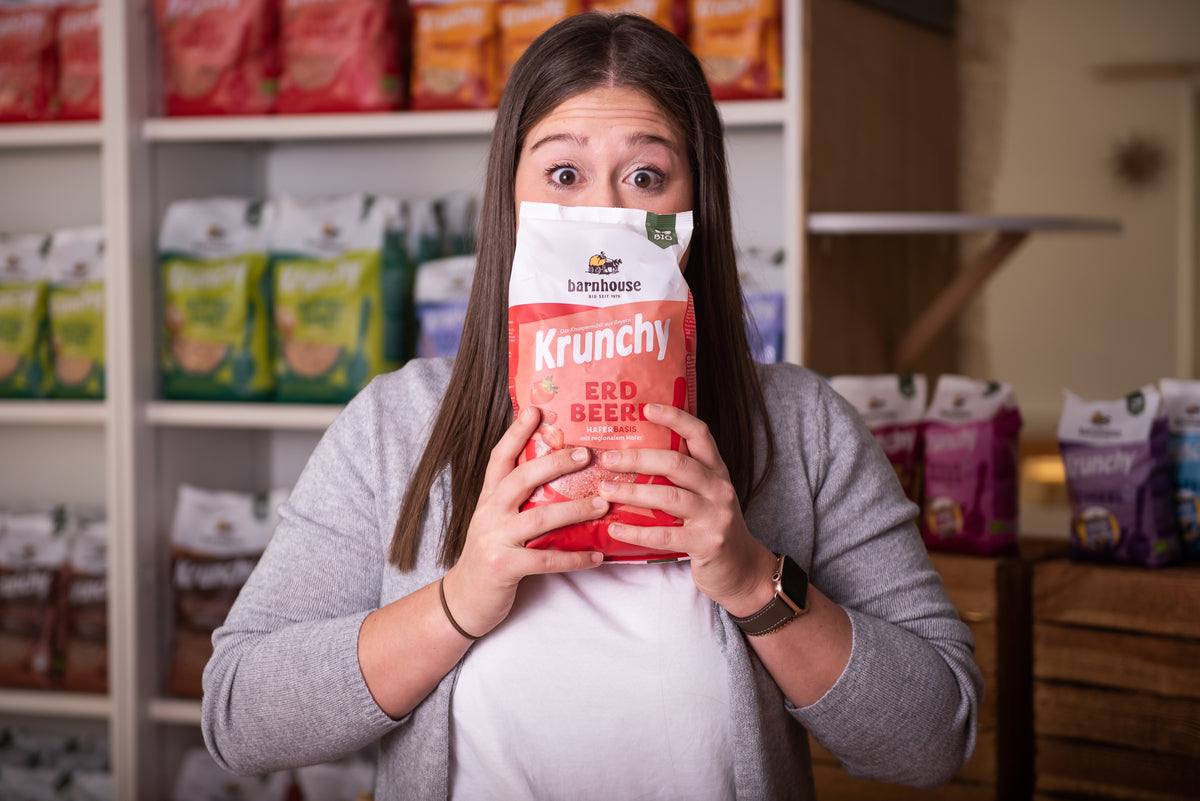 Spaßfoto: Kathi - Key-Account-Management Fachhandel - versteckt sich hinter einem Beutel Krunchy Erdbeere. Hinter ihr steht ein Regal mit Krunchy von Bio-Knuspermüsli-Hersteller Barnhouse.