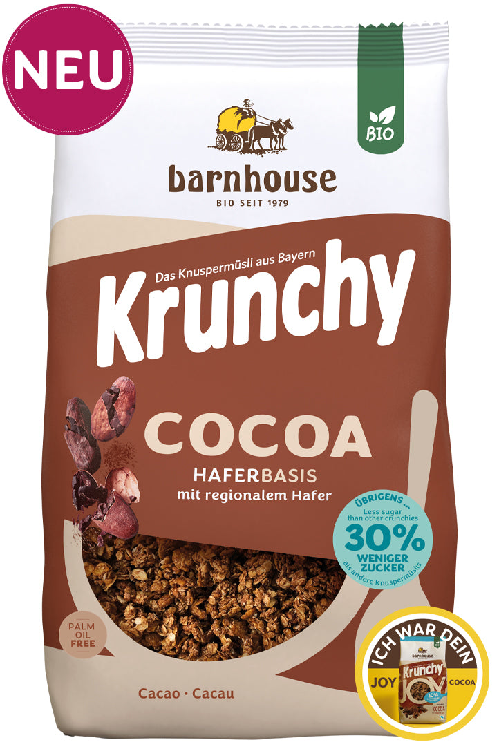 Packshot vom braun-beigen Beutel Krunchy Cocoa weniger Zucker von Bio-Knuspermüsli-Hersteller Barnhouse mit "Neu"und "Ich war dein Joy Cocoa" Button