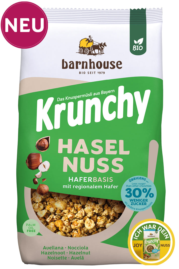 Packshot vom grünen-beigen Beutel Krunchy Haselnuss weniger Zucker von Bio-Knuspermüsli-Hersteller Barnhouse mit "Neu"und "Ich war dein Joy Nuss" Button