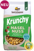 Packshot vom grünen-beigen Beutel Krunchy Haselnuss weniger Zucker von Bio-Knuspermüsli-Hersteller Barnhouse mit "Neu"und "Ich war dein Joy Nuss" Button