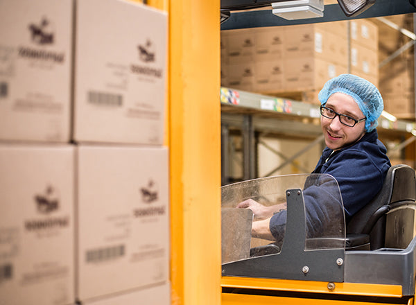 Chris fährt im Barnhouse Lager Krunchy Kartons mit dem Stapler an die richtige Position.