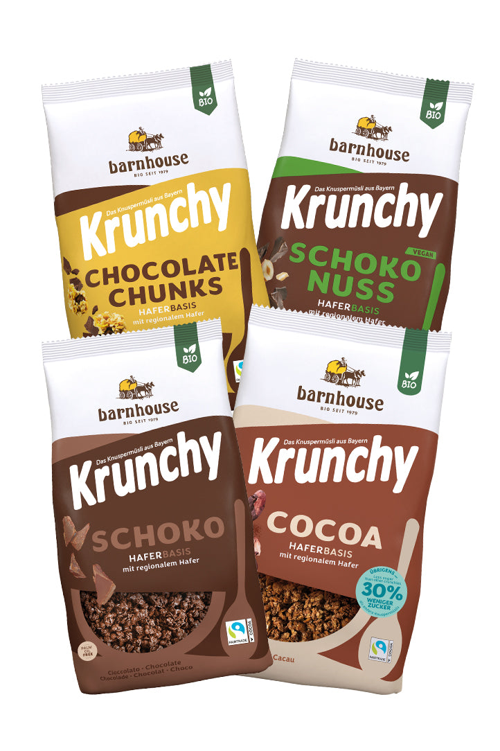 Blick von vorne auf die schräg in 2er Reihe angeordneten Packshots der vier Schoko-Krunchys Schoko-Nuss, Chocolate Chunks, Cocoa weniger Zucker und Schoko von Bio-Knuspermüsli-Hersteller Barnhouse.