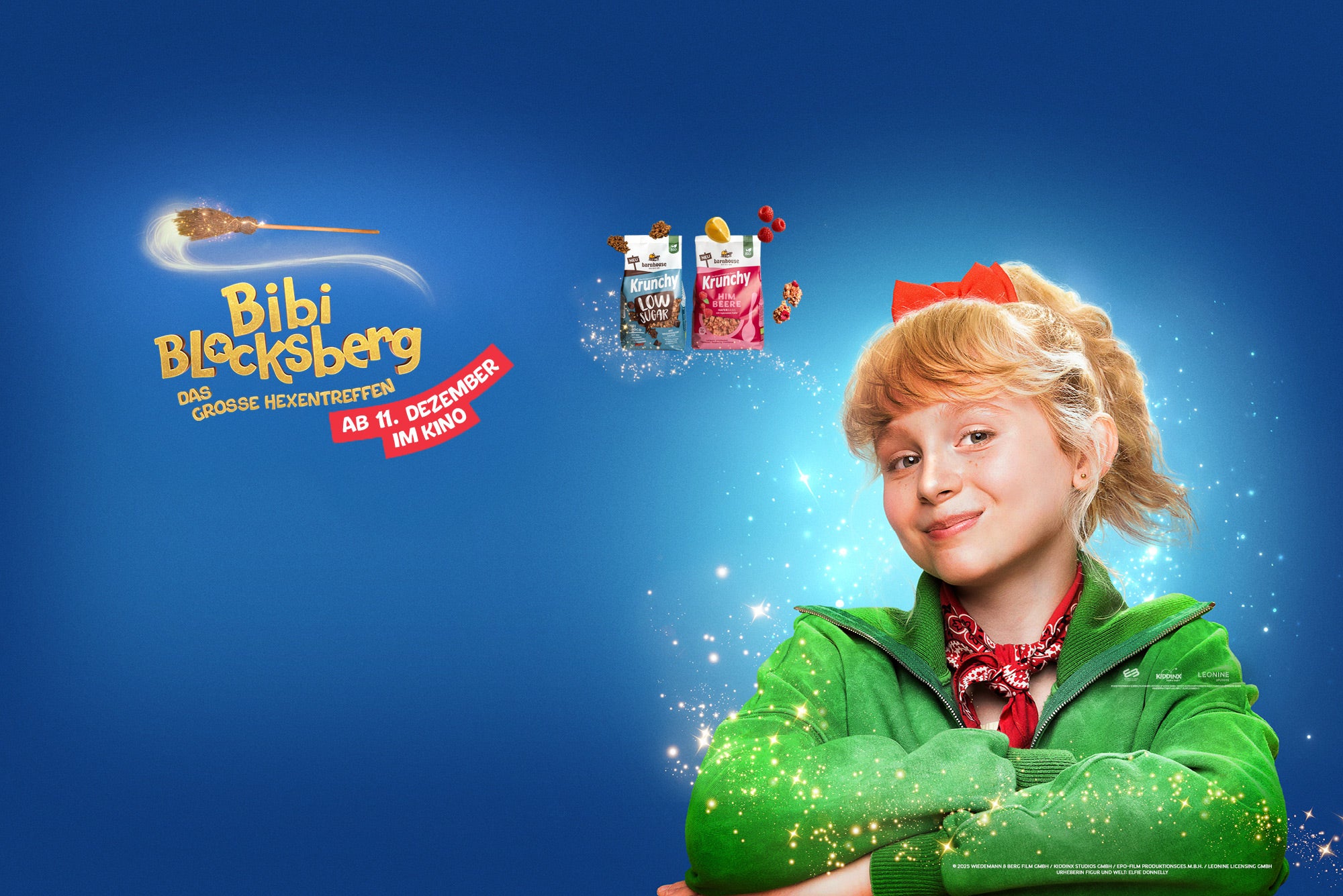 Blondes, junges Mädchen mit grüner Jacke und roter Schleife. Außenrum Glitzer. Darüber 2 Krunchy-Beutel, Cluster, Himbeeren & 1 Zitrone. Links steht "Bibi Blocksberg - DAS GROSSE HEXENTREFFEN ab 11. Dezember im Kino", darüber schwebt ein Hexenbesen.