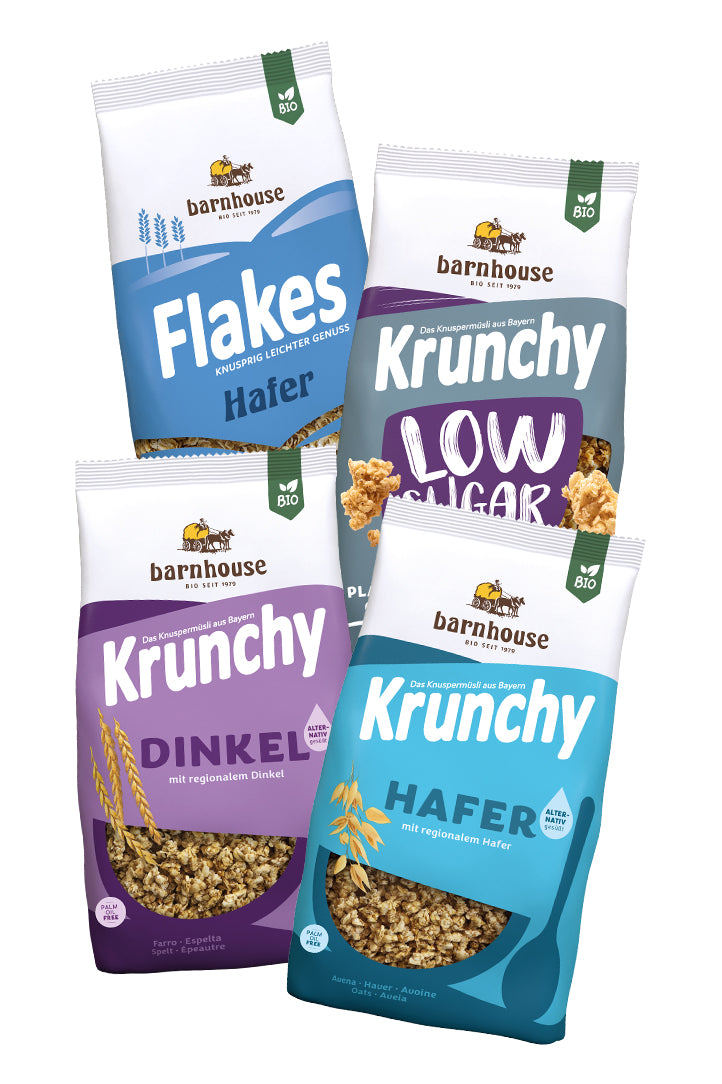 Blick von vorne auf die schräg in 2er Reihe angeordneten Packshots der vier Basis-Produkte Krunchy Low Sugar Plain Grain, Dinkel alternativ gesüßt, Hafer alternativ gesüßt sowie Flakes Hafer von Bio-Knuspermüsli-Hersteller Barnhouse.