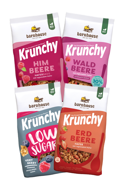 Blick von vorne auf die schräg in 2er Reihe angeordneten Packshots der vier Frucht-Krunchys Erdbeere, Waldbeere weniger Zucker, Low Sugar Very Berry sowie Himbeere von Bio-Knuspermüsli-Hersteller Barnhouse.
