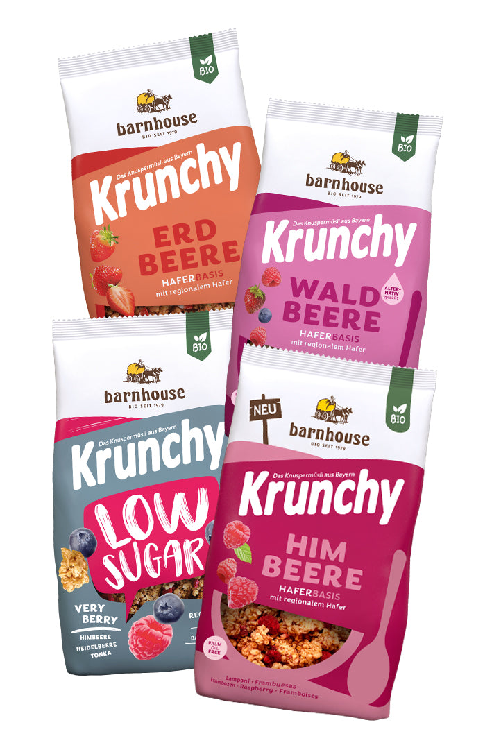 Blick von vorne auf die schräg in 2er Reihe angeordneten Packshots der vier Frucht-Krunchys Erdbeere, Waldbeere alternativ gesüßt, Low Sugar Very Berry sowie Himbeere von Bio-Knuspermüsli-Hersteller Barnhouse.