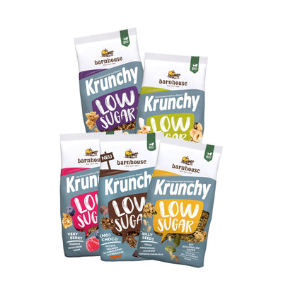 Blick von vorne auf die schräg angeordneten Packshots der fünf Low Sugar Krunchys Plain Grain, Crazy Nuts, Very Berry (No) Choco und Silly Seeds von Bio-Knuspermüsli-Hersteller Barnhouse.