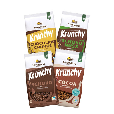 Blick von vorne auf die schräg in 2er Reihe angeordneten Packshots der vier Schoko-Krunchys Schoko-Nuss, Chocolate Chunks, Cocoa weniger Zucker und Schoko von Bio-Knuspermüsli-Hersteller Barnhouse.